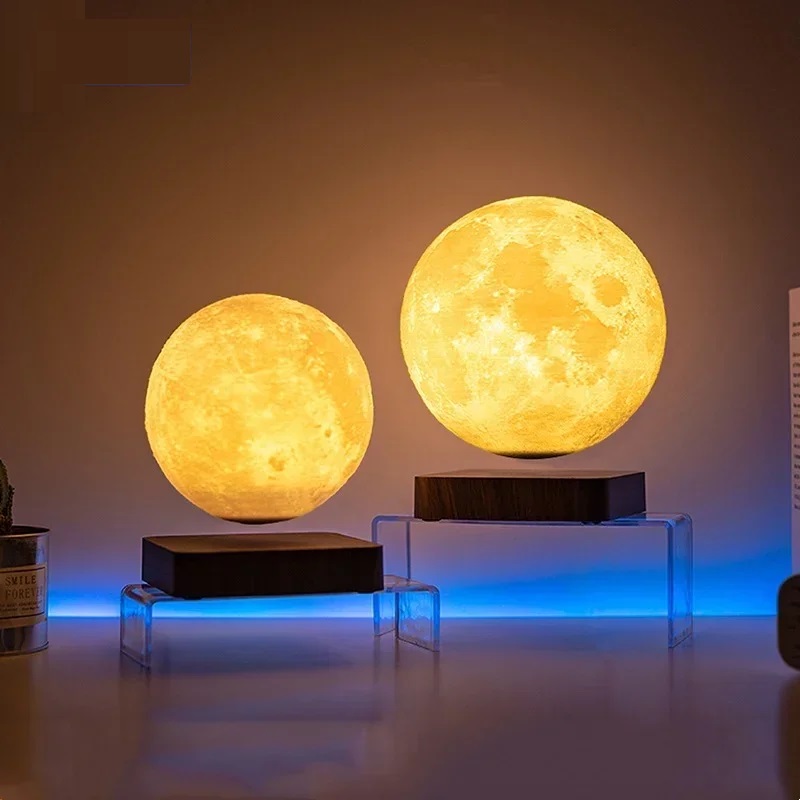 Two Floating Moon Lamps of different sizes rest on transparent stands, casting a warm glow in a dimly lit room complemented by a blue light accent in the background. The ambiance evokes the charm of the best Floating Moon Lamp without disrupting the serene atmosphere.