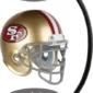 A miniature golden helmet with "SF" logo, suspended between two black magnetic bases, creating a levitating effect.