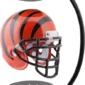 A black and orange striped football helmet is suspended in mid-air between two black magnetic bases.