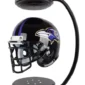 A black football helmet with a purple and white bird logo is levitating between two black magnetic holders.
