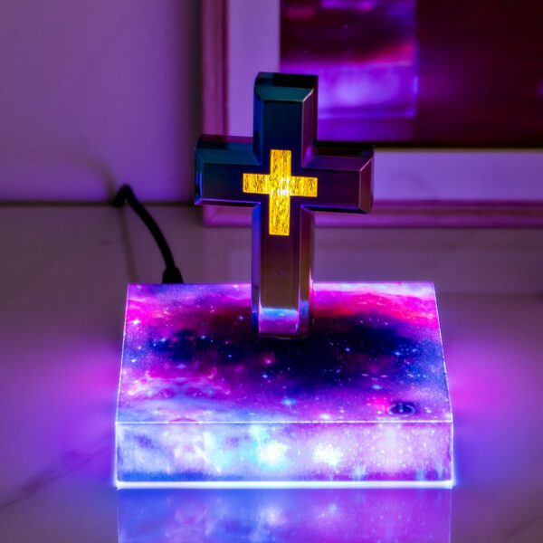 0-levitating cross nightlight with starry base The Floating Cross Nightlight features an illuminated Greek cross standing on a vibrant, galaxy-themed base, casting ambient lighting across its surface.