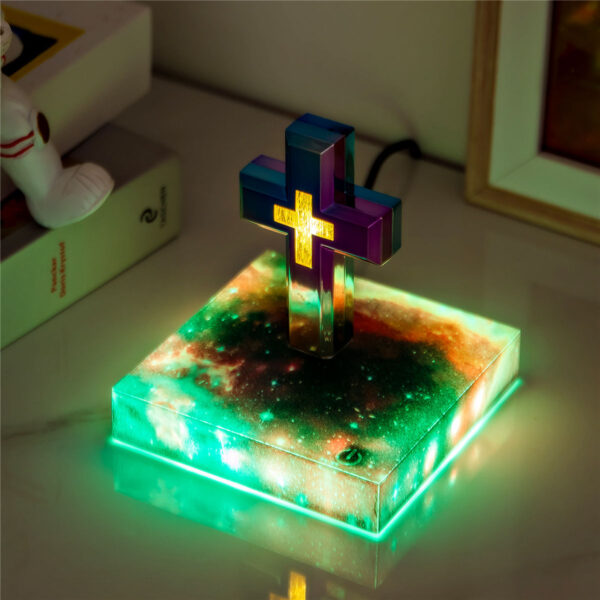 2-levitating cross nightlight with starry base The Floating Cross Nightlight, shaped like a Greek cross and adorned with multiple colors, rests on a glowing square base with a cosmic design.