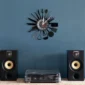 Wall clock with kitchen utensil design as hour markers, mounted on a blue wall above a turntable and speakers.