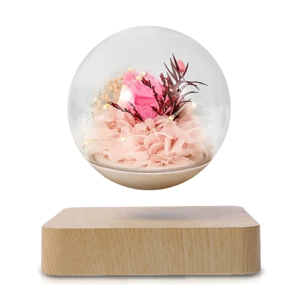 Magnetic Levitating Preserved Flower Rotation Flower Lamp Creative Floating LED Night Light For Home Desk Office Decoration 2 A levitating glass orb with pink flowers and foliage inside, held above a wooden base.