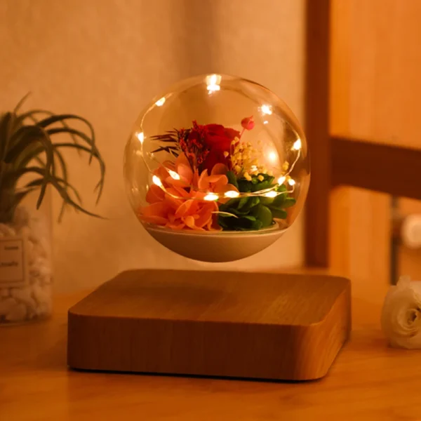 Magnetic Levitating Preserved Flower Rotation Flower Lamp Creative Floating LED Night Light For Home Desk Office Decoration 4 A glass orb with illuminated flowers inside floats above a wooden base, positioned on a wooden surface.