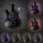 Six guitar-shaped wall clocks with illuminated edges in different colors are mounted on a brick wall.