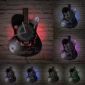 Wall-mounted guitar-shaped clock with musical notes, featuring colorful LED lights in different hues against a brick wall backdrop.