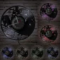 Round wall clocks with musical and instrument motifs are displayed against a brick wall. Each clock is illuminated with different colored lights.