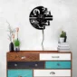 Wall-mounted sci-fi-themed clock above a colorful chest of drawers, with stacked books, cacti, and candle holders.