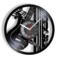 A wall clock designed with a vinyl record motif, featuring musical notes, a guitar, and piano keys. The clock has white hour and minute hands, and a red second hand.