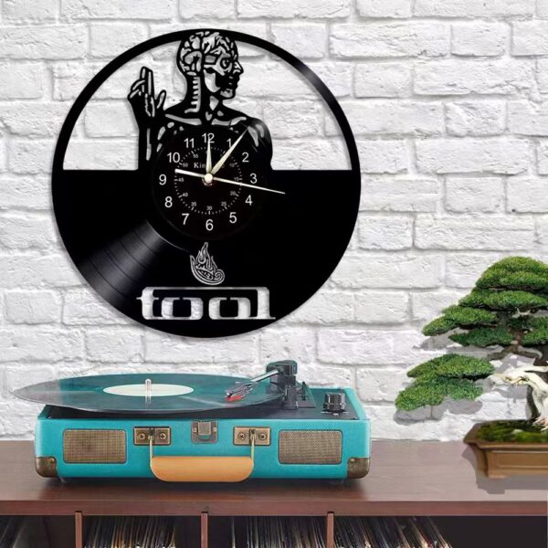 Skeletal Brain Wall Clock 6 A Skeletal Brain Wall Clock with a figure design above the word "Tool" hangs on a white brick wall. Below, a turquoise suitcase-style record player and a bonsai tree are placed on a wooden shelf.