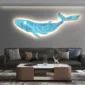 A room with a gray sofa, patterned pillows, a modern coffee table, and a glowing whale-shaped light fixture mounted on the wall.