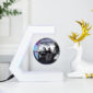 A black and silver globe levitates within a C-shaped magnetic holder on a white desk, next to a white decorative deer with gold antlers.